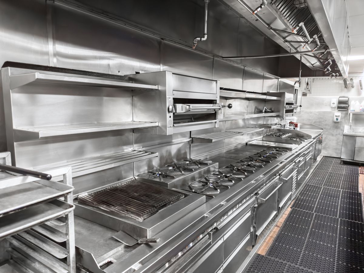 Stainless steel exhaust canopy above a commercial kitchen cooking line