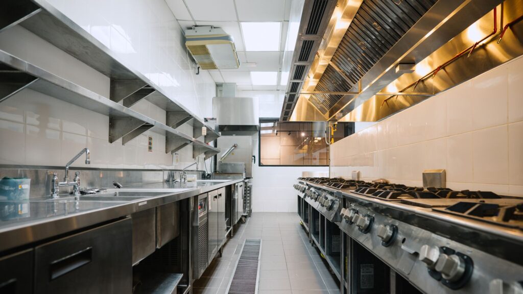 Stainless steel exhaust canopy running above a commercial kitchen cooking line