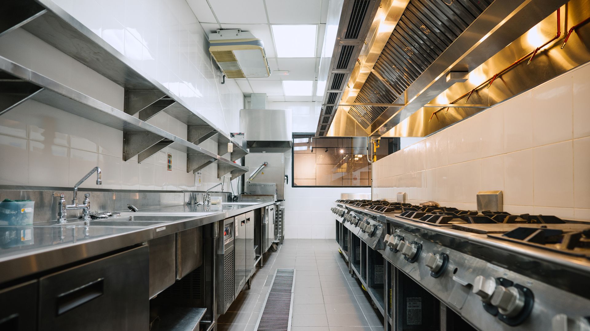 Stainless steel exhaust canopy running above a commercial kitchen cooking line