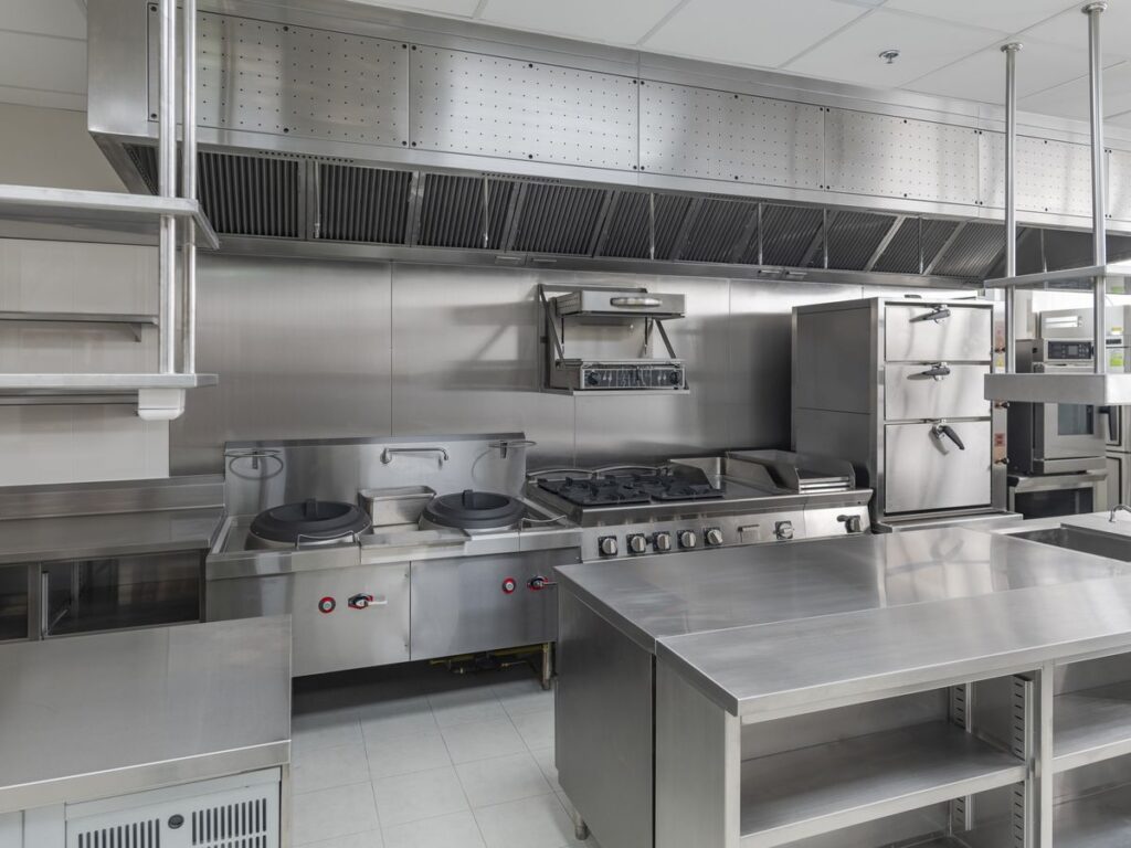 Completed commercial kitchen fitout with stainless steel benches and exhaust canopy