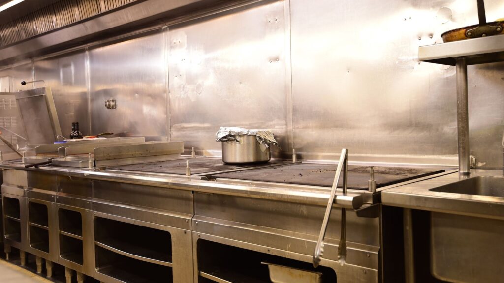 Commercial kitchen cooking line with full-height stainless steel splashback panels