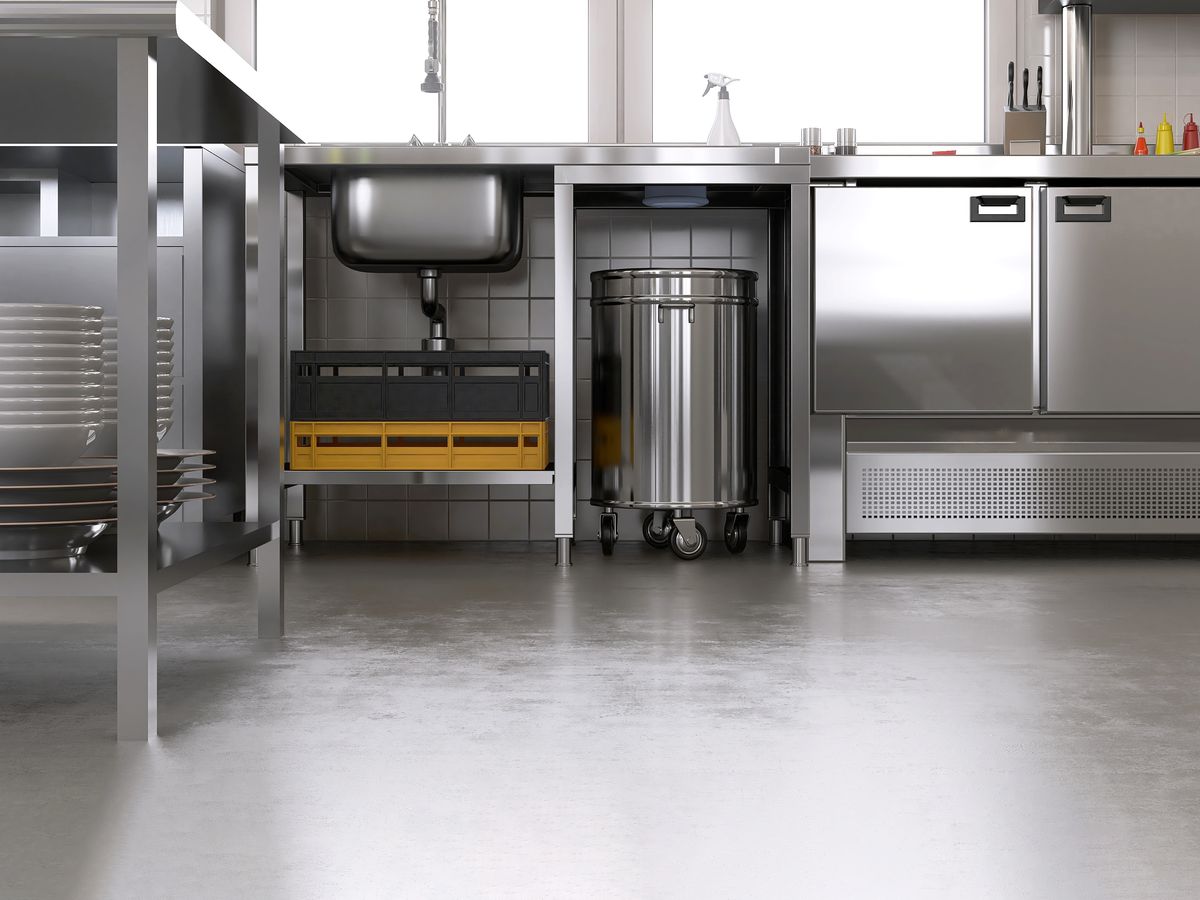 Stainless steel sink bench with undershelf and under-bench refrigeration in a commercial kitchen