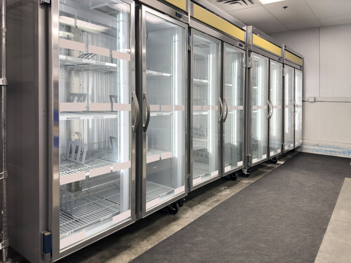Row of glass-door upright commercial fridges in a food storage area