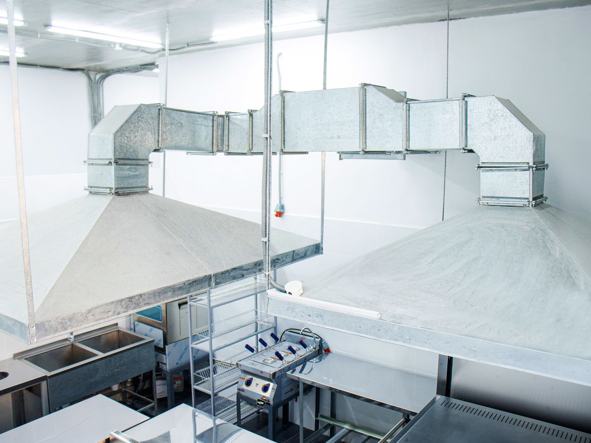Island exhaust canopies with ducting above a commercial kitchen cooking line