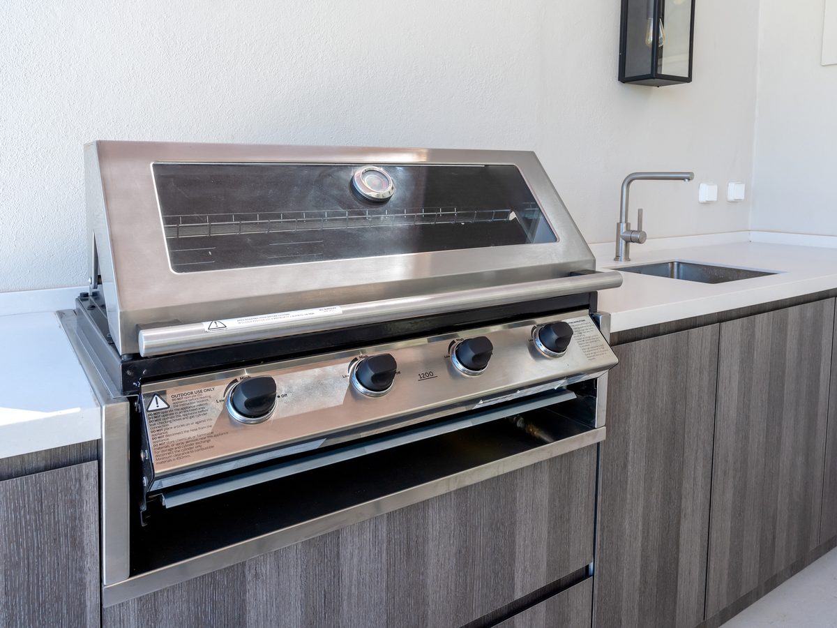 Built-in stainless steel BBQ beside an outdoor kitchen sink bench