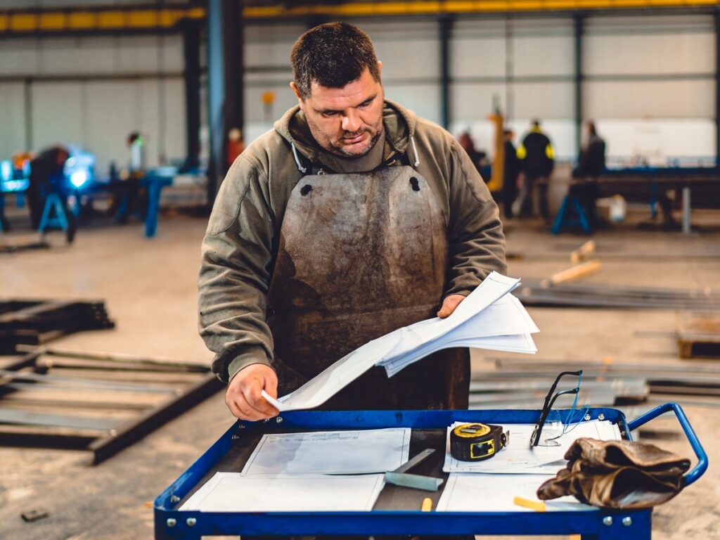 Fabricator reviewing a fabrication drawing at a workshop bench