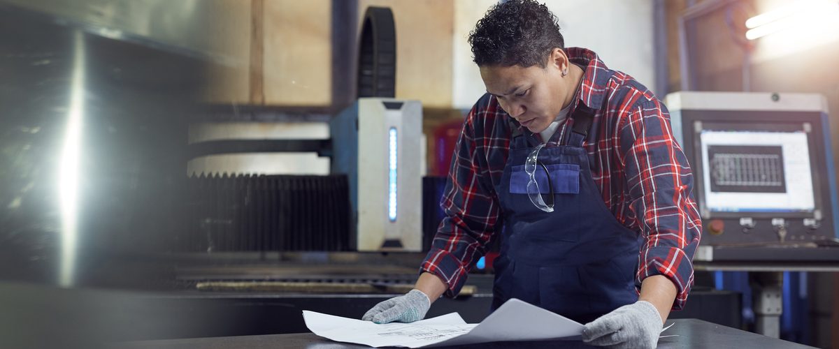 Fabricator checking a drawing on a steel table in a fabrication workshop