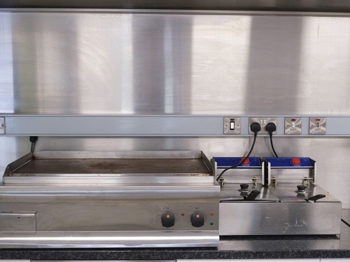 Power points set into a stainless steel splashback above a griddle and fryer